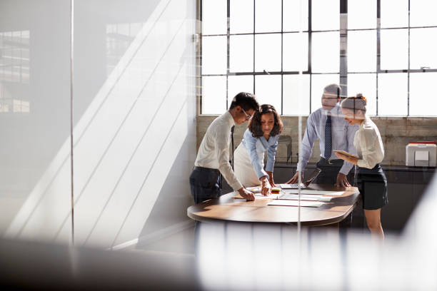 four business colleagues stand talking in a meeting room - teamwork team business meeting imagens e fotografias de stock