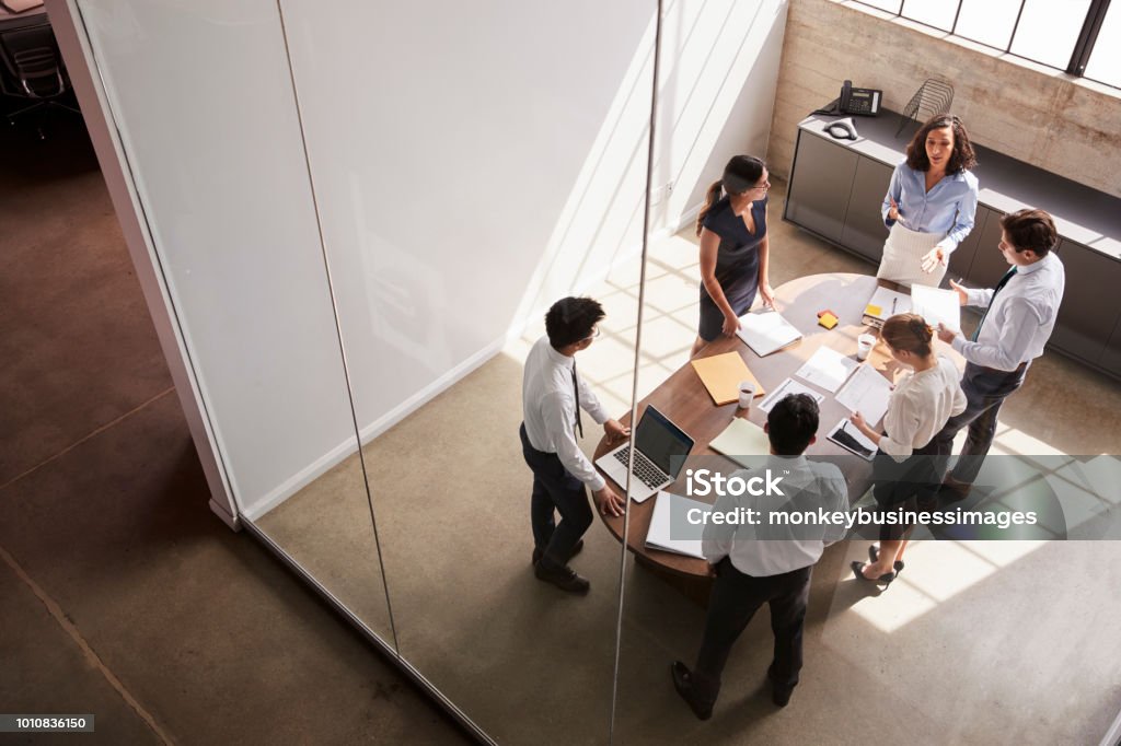 Female manager in team meeting, elevated view through window Business Stock Photo