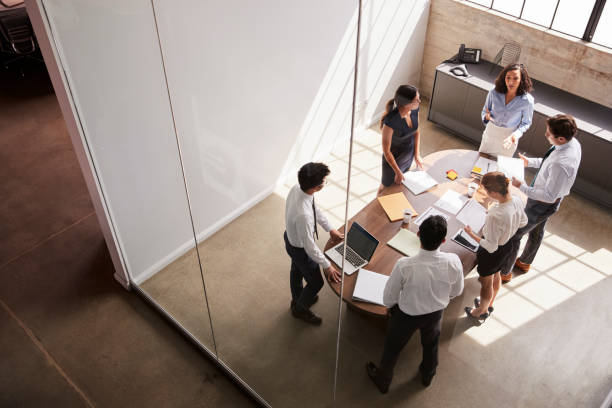 female manager in team meeting, elevated view through window - concentration multi ethnic group meeting business imagens e fotografias de stock