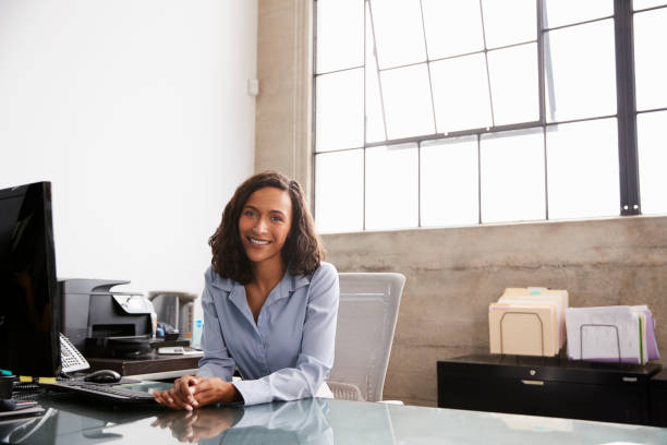 istock Young mixed race woman at office desk smiling to camera 1010837148