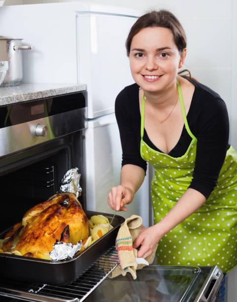 istock Cheerful woman roasting cockerel for dinner 1010843654