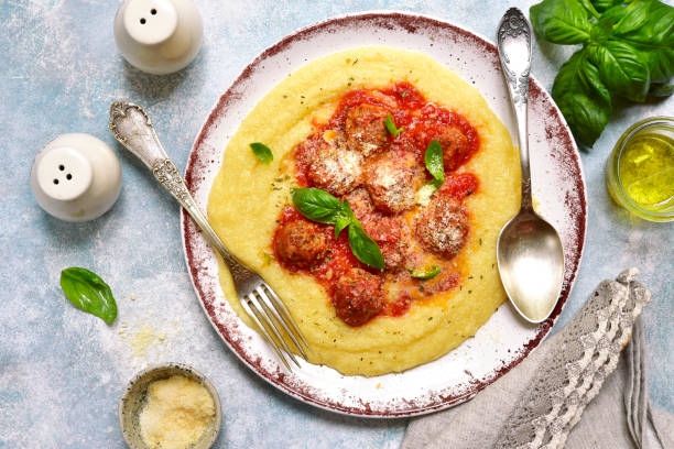 Polenta with meatballs in tomato sauce Polenta with meatballs in tomato sauce on a plate over light blue slate, stone or concrete background.Top view. croatian culture photos stock pictures, royalty-free photos & images