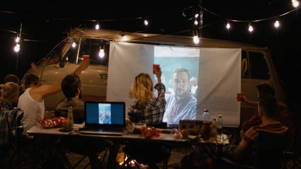 istock Friends watching movie on screen in campsite 1010850176