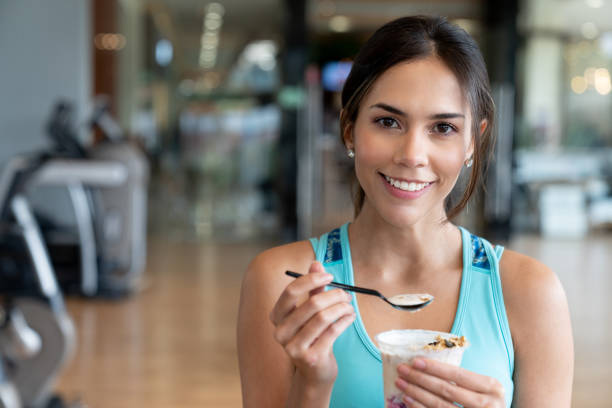 mujer de comer una merienda saludable en el gimnasio - yogur fotos fotografías e imágenes de stock