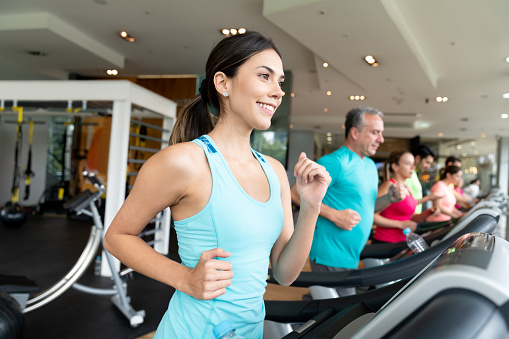 Portrait of a happy woman at the gym running on the treadmill and smiling â fitness concepts