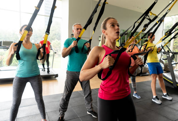 Instructor teaching a suspension training class at the gym Instructor teaching a suspension training class at the gym to a group of Latin American people â fitness concepts suspension training stock pictures, royalty-free photos & images