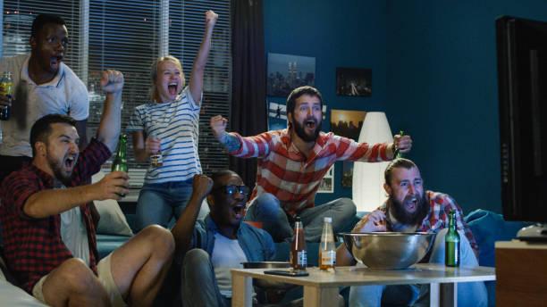 Excited fans cheering for sport team watching game View of diverse men and woman with beer and popcorn spilled cheering for winner team while watching sport game tv game stock pictures, royalty-free photos & images