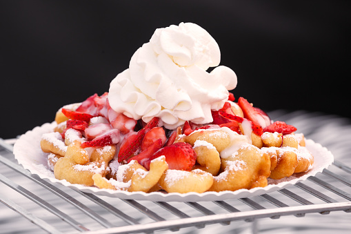 Funnel cake with sugar, strawberries and whipped cream at a USA fourth of July celebration