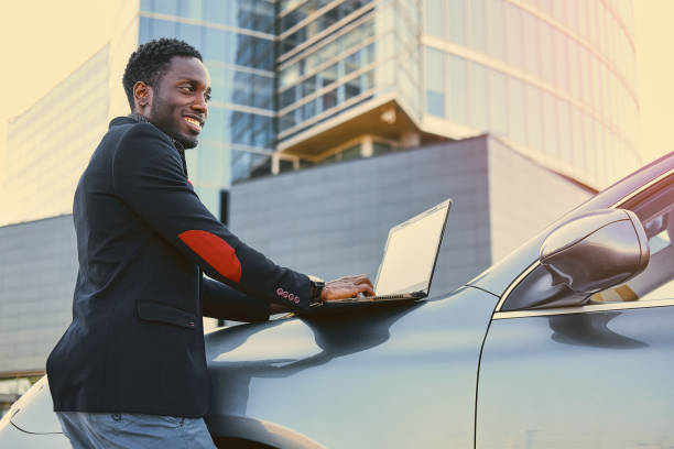 istock Black male using a laptop on car's hood. 1010903220