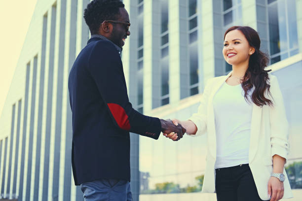 istock Black man and Caucasian female handshake over modern building. 1010911662