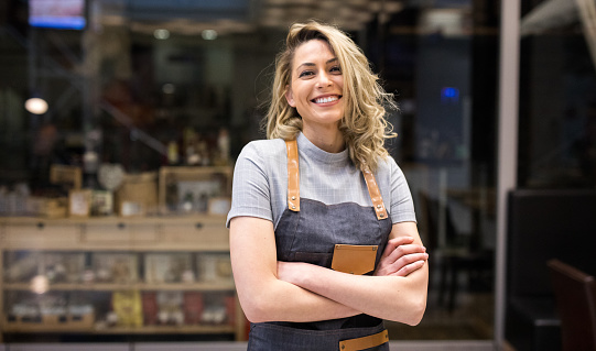 Portrait of Smiling cafeteria owner standing with arms crossed