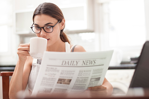 woman reading news and drink coffee at the kitchen