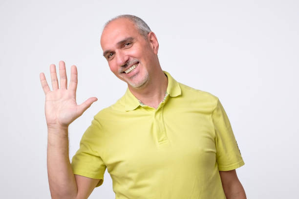 istock Friendly-looking attractive european man waiving hand in hello gesture while smiling cheerfully. 1010933712