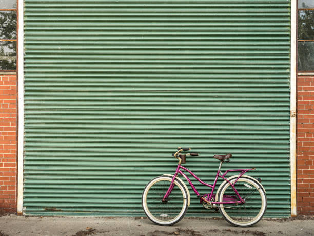 Wide angle image of cruiser design lady bicycle parked against rustic aluminum shutter gate. Urban setting of large North American city.