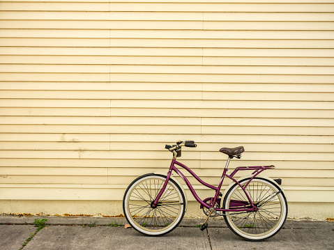 Wide angle image of cruiser design lady bicycle parked against rustic facade wall on the street sidewalk. Urban setting of large North American city.