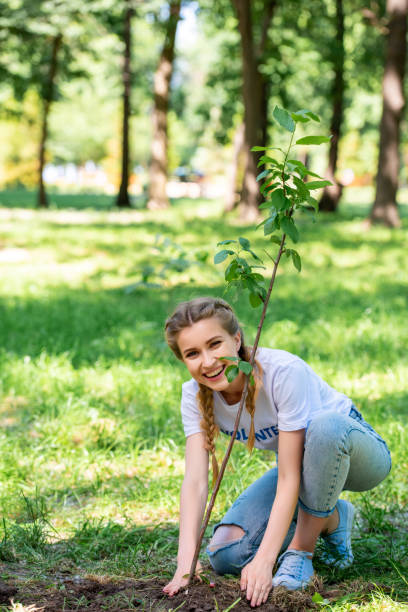 istock smiling beautiful volunteer planting new tree in park 1010948704