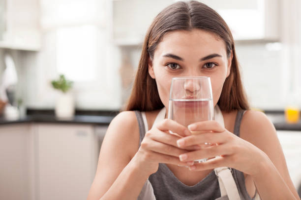 istock woman drinking water at the kitchen 1010949274