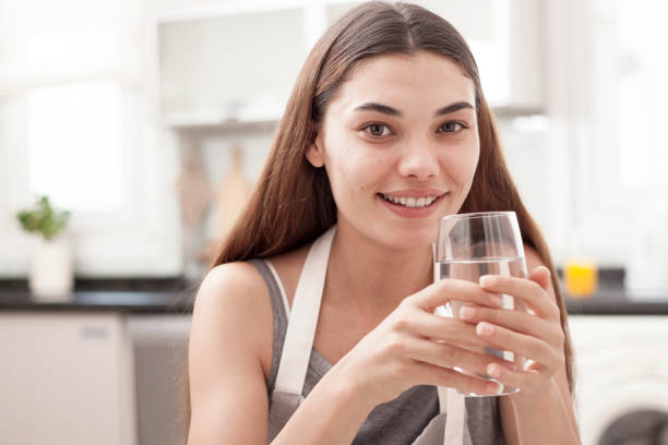 istock woman drinking water at the kitchen 1010949290