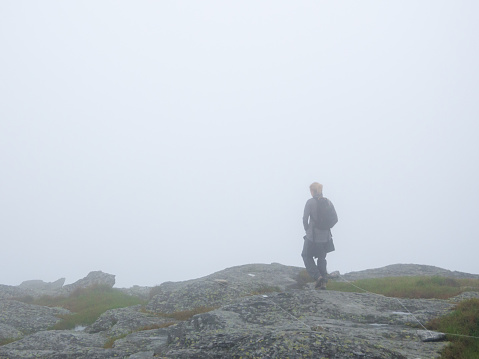 A lonely woman walking on the top of a mountain on a misty summer day