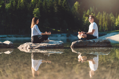 Couple spending time together and doing yoga by the lake