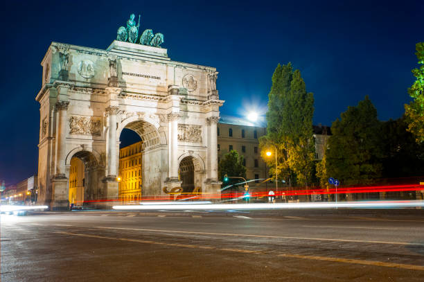 Victory Gate in Munich Traffic navigates past Munich's triumphal arch at night. siegestor stock pictures, royalty-free photos & images