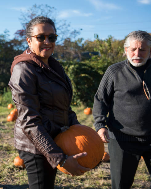 istock Three senior friends picking pumpkins at Pumpkin Patch 1010978830