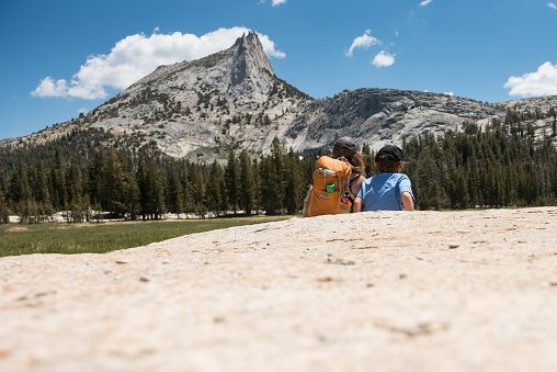 Brave and strong child embarks on a 7 miles hike up to Cathedral Peak in Tuolumne Meadows in Yosemite Valley National Park in California. Beautiful landscape with child exploring, running and playing.