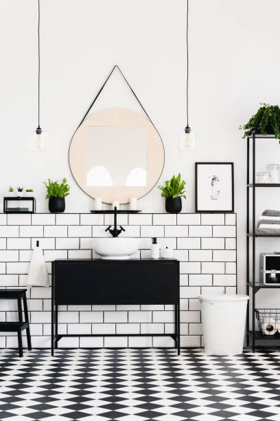 istock Mirror between plants above black washbasin in contrast bathroom interior with poster. Real photo 1010984390