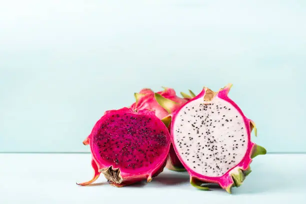 Half red and white dragon fruit on color background, tropical fruit