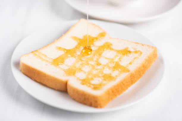 Close-up of golden honey being poured over French toast topped with fresh strawberries and blueberries