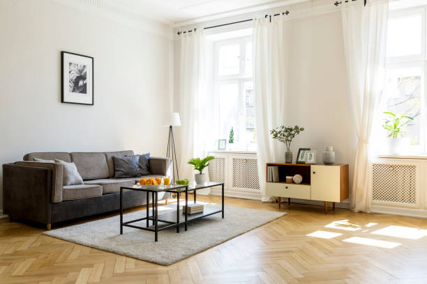 istock Black table on carpet in spacious living room interior with poster above grey settee. Real photo 1010992718