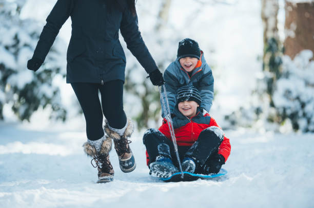 istock Mom pulls her son through the snow on a sled 1010992966