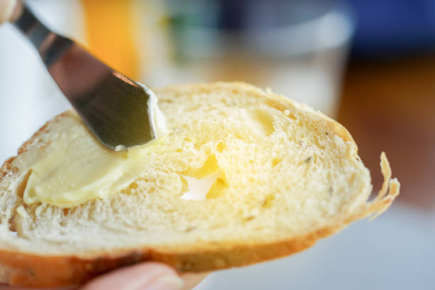 istock Hands spreading butter on bread, closeup shot 1010993230