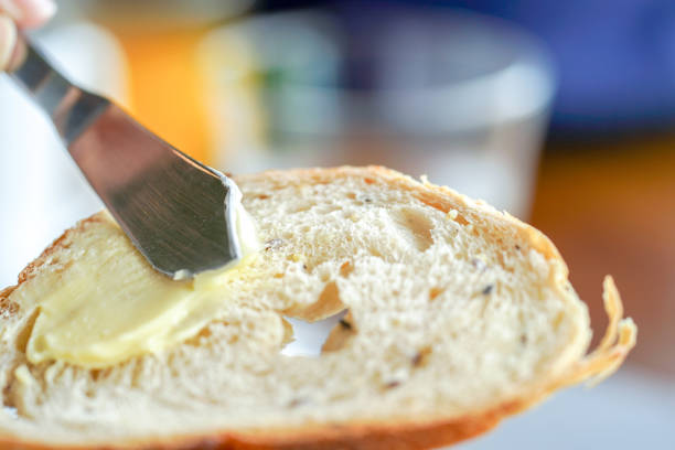 istock Hands spreading butter on bread, closeup shot 1010993234