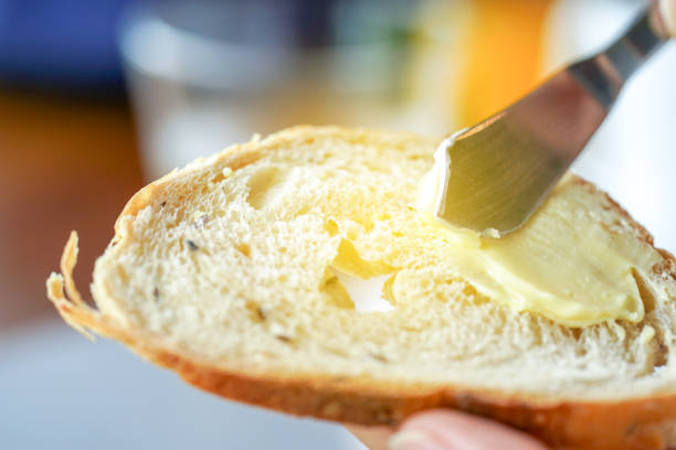 istock Hands spreading butter on bread, closeup shot 1010993238
