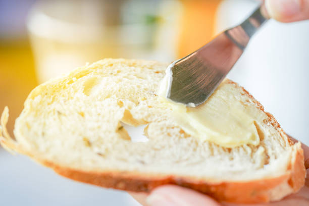 istock Hands spreading butter on bread, closeup shot 1010993244