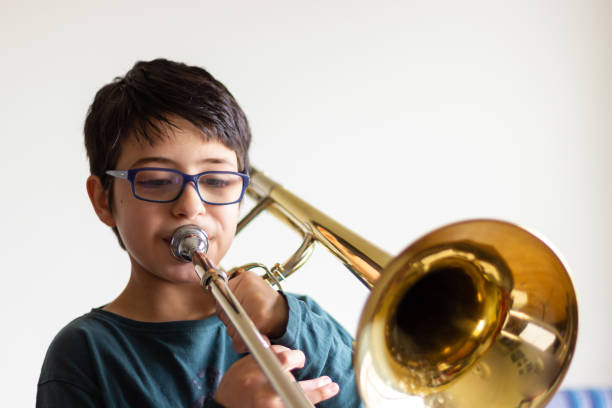 Boy playing trombone Boy playing trombone at home juvenile musician stock pictures, royalty-free photos & images