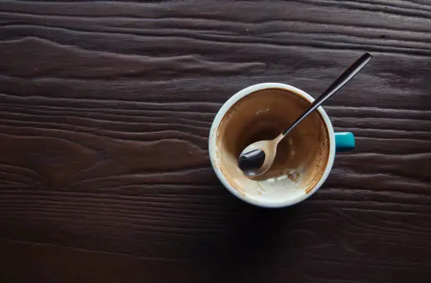 Top view a cup of coffee and spoon on wooden table.