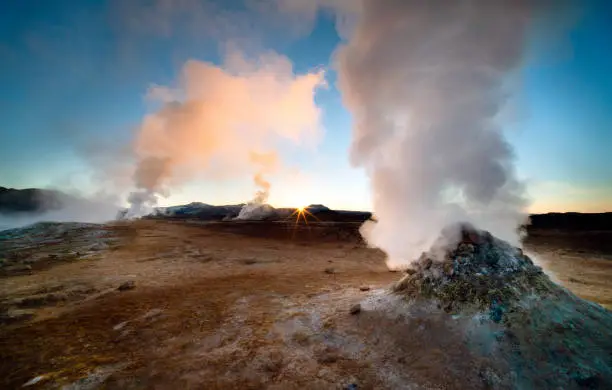 A beautiful dawn in Iceland, a country with many geothermal features including these dramatic fumaroles. Shot with a wide angle lens for dramatic effect and a small aperture to create a sunstar where the sun is just peaking over the horizon. The scenery in Iceland is spectacular and it is becoming a popular tourist destination.