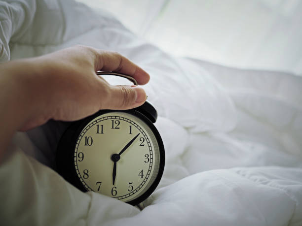 istock hand holding alarm clock in the morning 1011072888