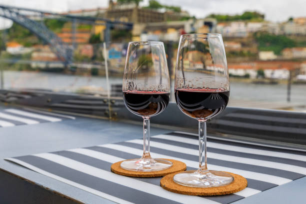 glass of port wine with the blurred cityscape of porto portugal in the background - vinho do porto imagens e fotografias de stock