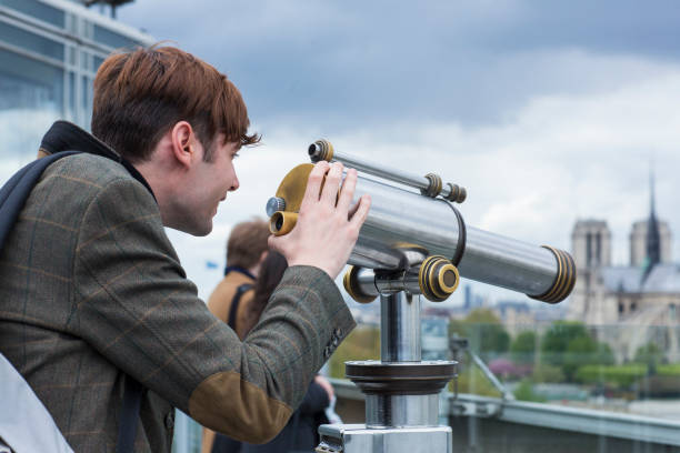 istock Man smiling and looking through a telescope over paris 1011081746