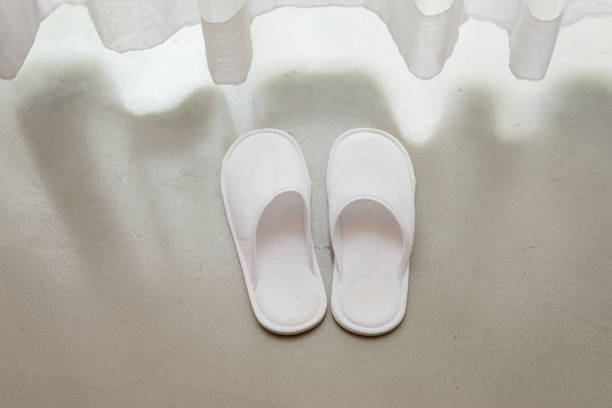 low section of young overweight woman in white slippers and bathrobe on pink