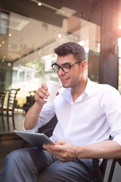istock Young businessman working in coffee shop using smartphone. 1011110190
