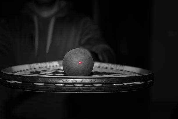 einzelner punkt squash ball auf den saiten eines schlägers - squash racket stock-fotos und bilder