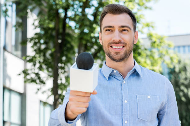 istock smiling male journalist taking interview with microphone 1011128544