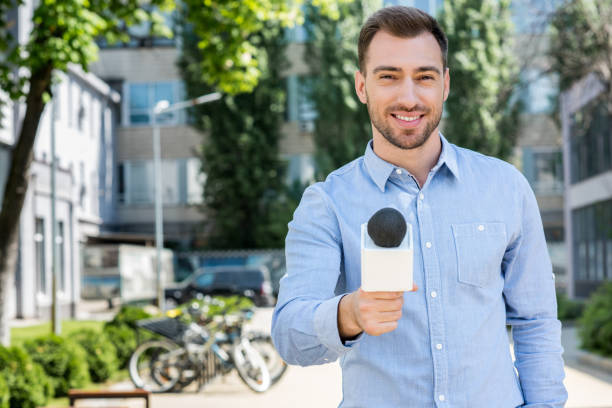 istock smiling male news reporter taking interview with microphone 1011128670