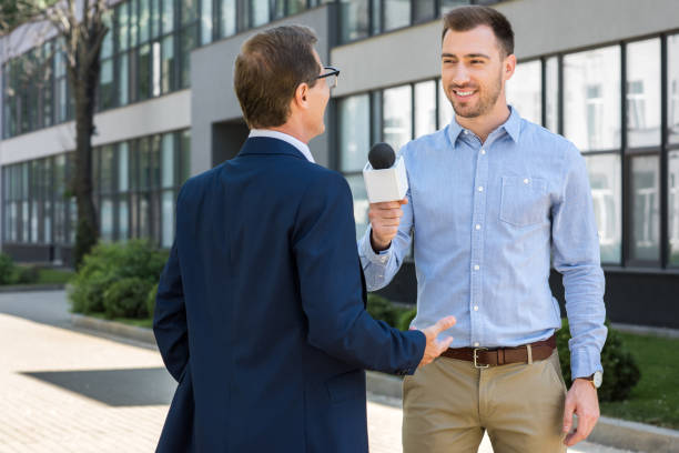 istock professional smiling journalist interviewing successful mature businessman with microphone 1011128766