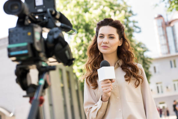istock beautiful female journalist with microphone talking to digital video camera 1011129194
