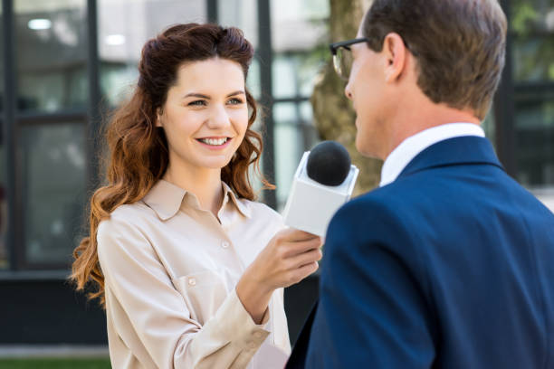 istock beautiful news reporter with microphone interviewing businessman 1011129218
